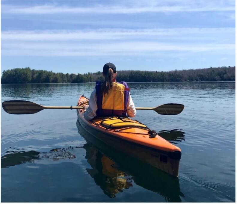 how to kayak - female in orange kayak.  