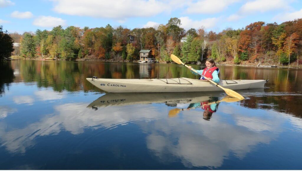 young girl kayaking on a calm lake