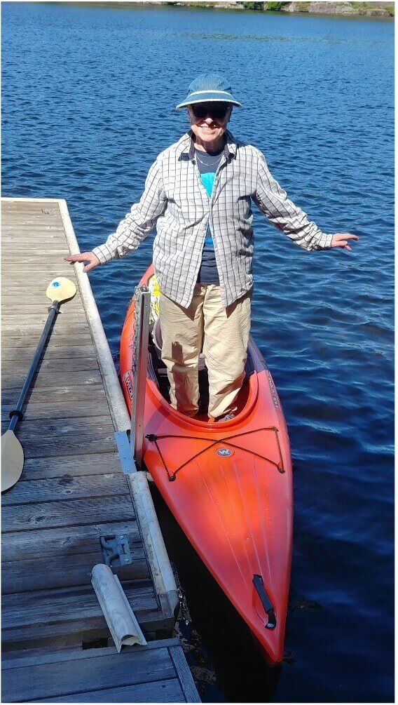 person in a red kayak beside a dock